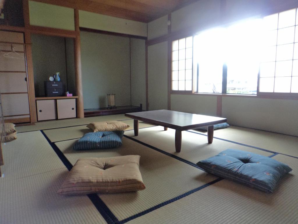 a room with a table and pillows on the floor at Konpira House in Kotohira
