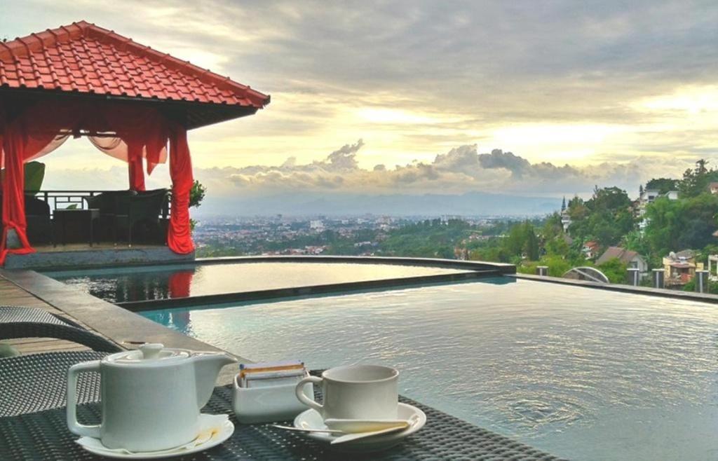 two coffee cups on a table next to a swimming pool at Dago Highland Resort in Bandung