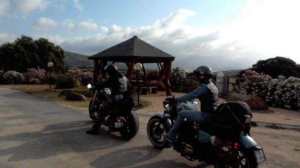 zwei Personen, die auf einer Straße mit Pavillon Motorrad fahren in der Unterkunft Agriturismo Pedru Caddu in Tula