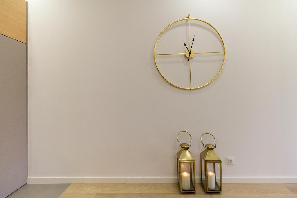 a clock on a wall with two gold bottles at The Office Guest in Guimarães