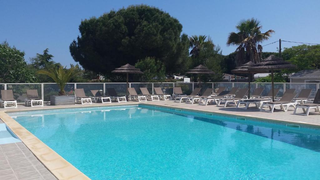 uma grande piscina com espreguiçadeiras e guarda-sóis em Camping Les Roches d'Agde em Le Grau-dʼAgde