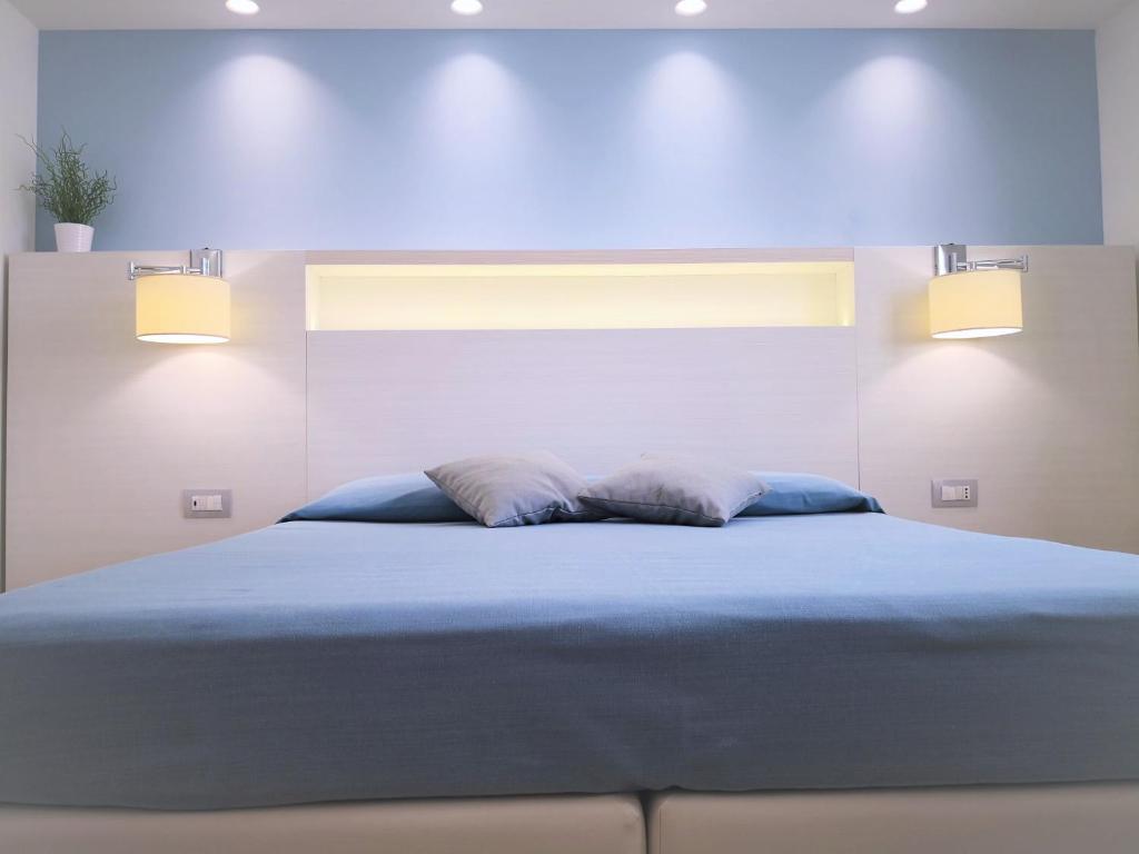 a bedroom with a bed with blue sheets and two pillows at Hotel Perla Gaia in San Vito lo Capo