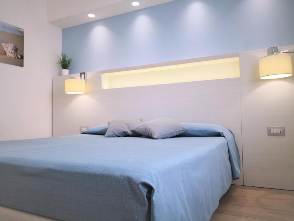 a bedroom with a blue bed with two pillows at Hotel Perla Gaia in San Vito lo Capo