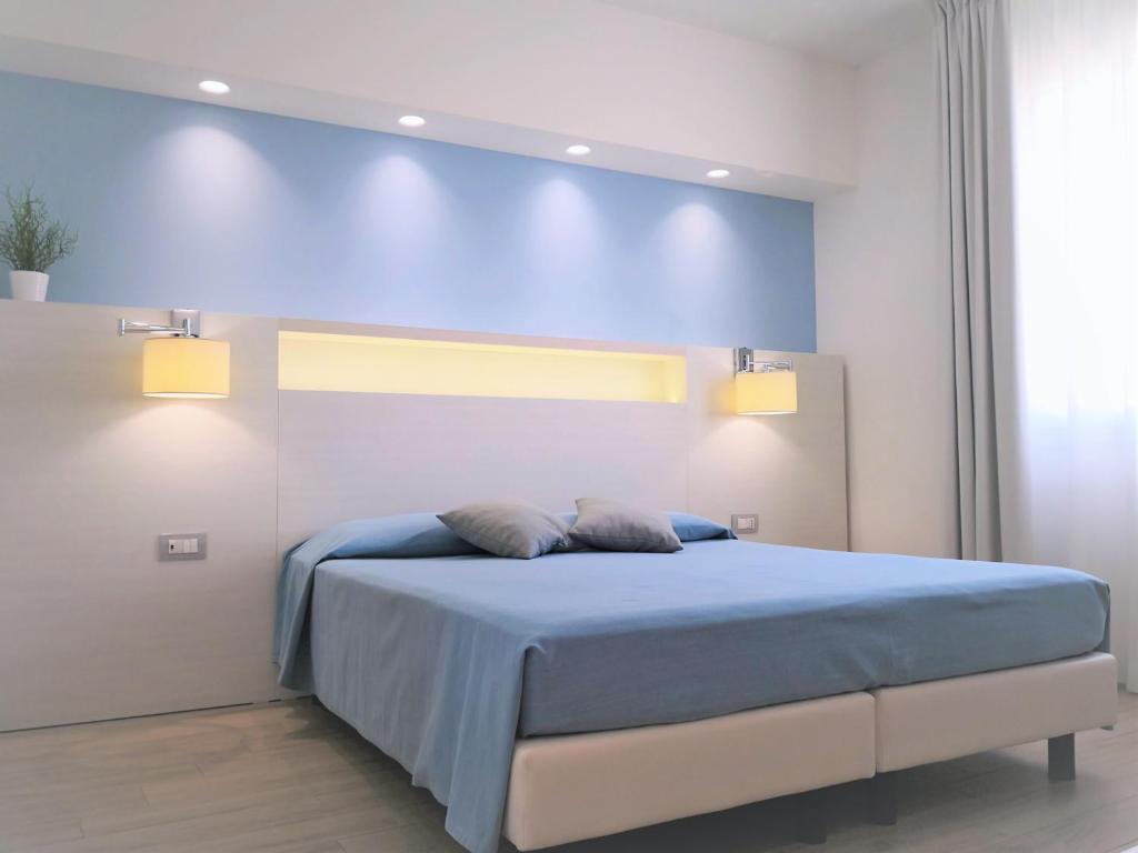 a bedroom with a bed with a blue wall at Hotel Perla Gaia in San Vito lo Capo