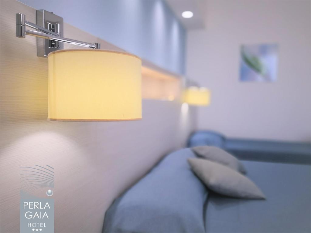 a room with a bed with a lamp and a pillow at Hotel Perla Gaia in San Vito lo Capo