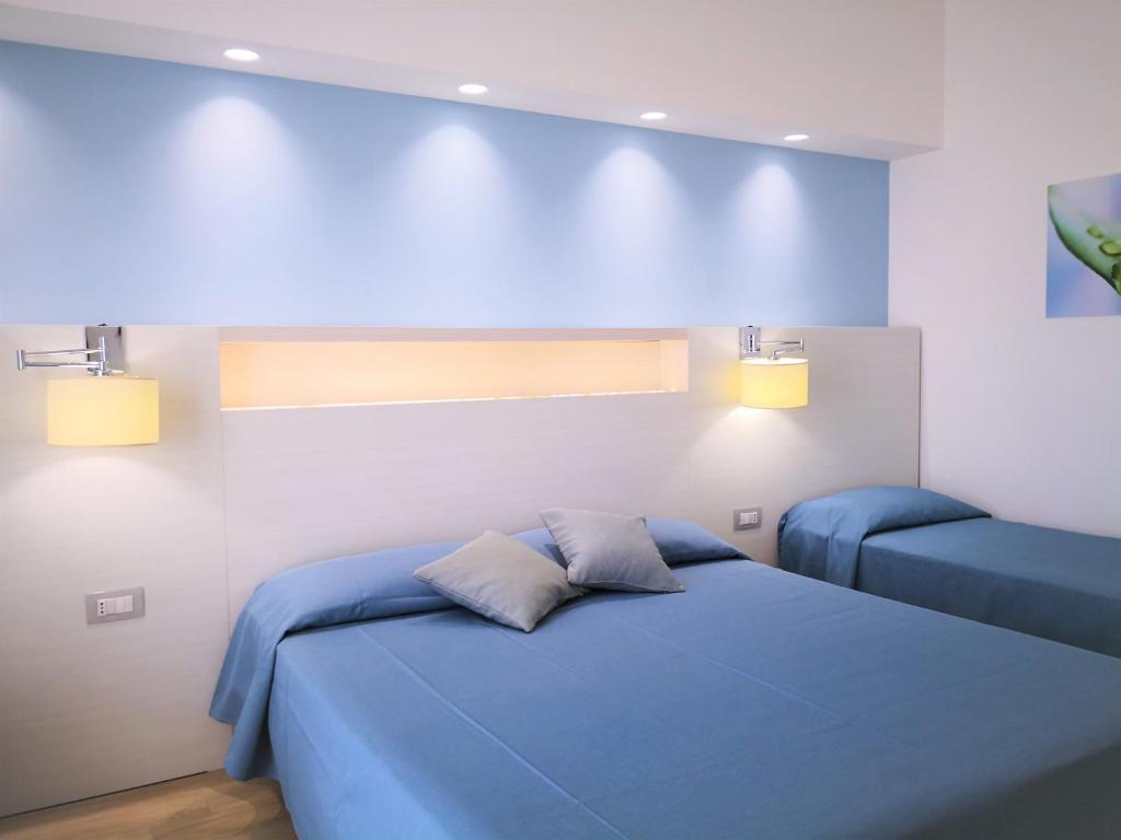 a bedroom with a blue bed and two lights at Hotel Perla Gaia in San Vito lo Capo