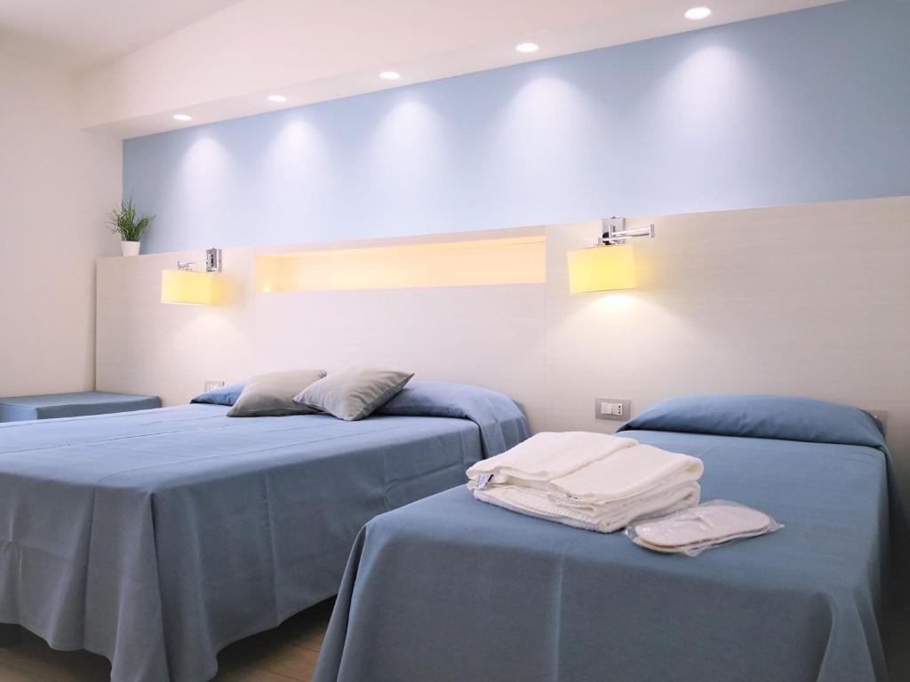 two beds in a room with blue sheets at Hotel Perla Gaia in San Vito lo Capo