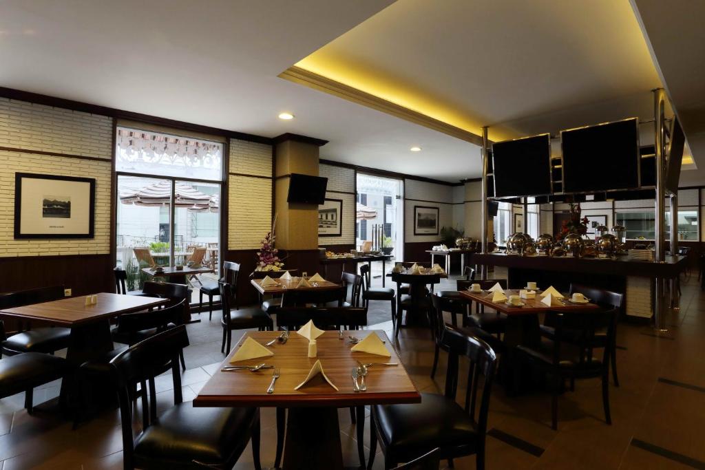 Amarelo Hotel Solo في سولو: مطعم فيه طاولات وكراسي في الغرفة