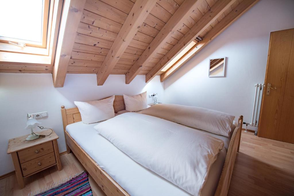 una camera da letto con un grande letto bianco e un soffitto in legno di Ferienwohnung Fauser a Oberstdorf