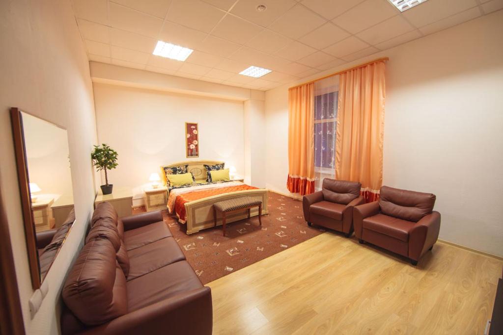 a bedroom with a bed and a couch and chairs at Hotel Orion in Surgut
