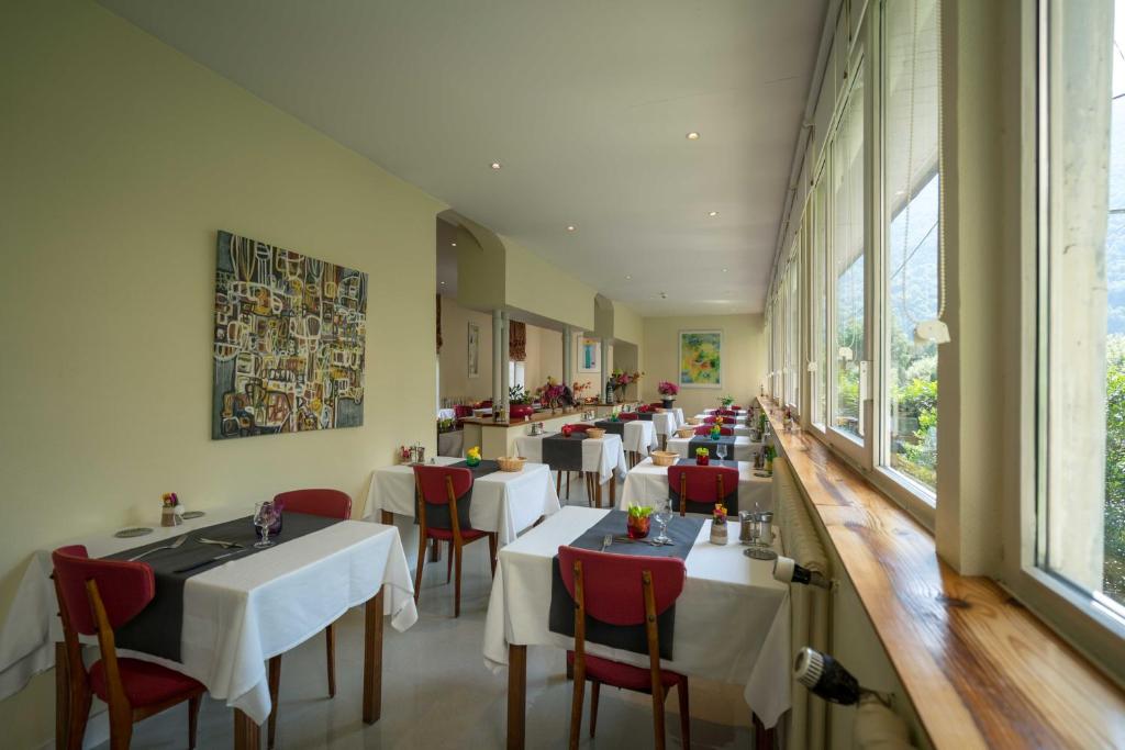 a dining room with tables and chairs and a large window at Hôtel Aquitaine in Luchon