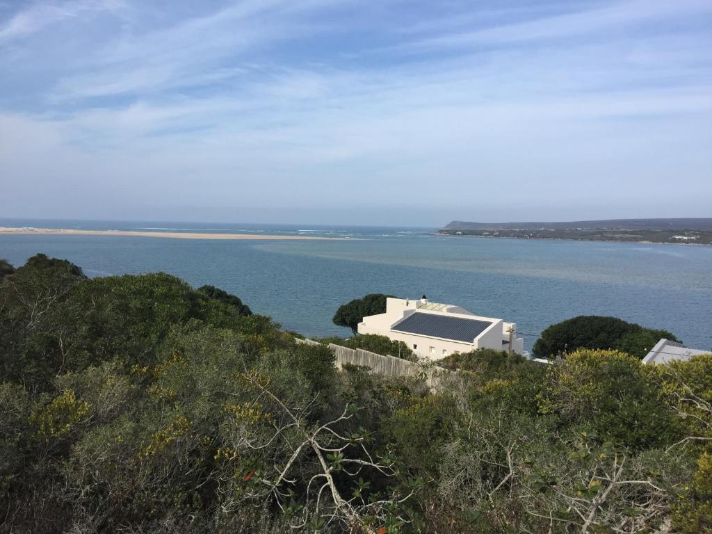 ein Gebäude auf einem Hügel neben einem Wasserkörper in der Unterkunft Breede View Holiday Home in Witsand