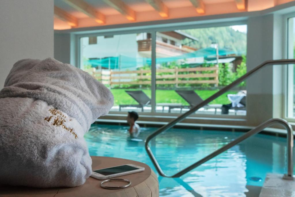 a towel sitting on a table next to a swimming pool at Hotel El Paster in Pozza di Fassa