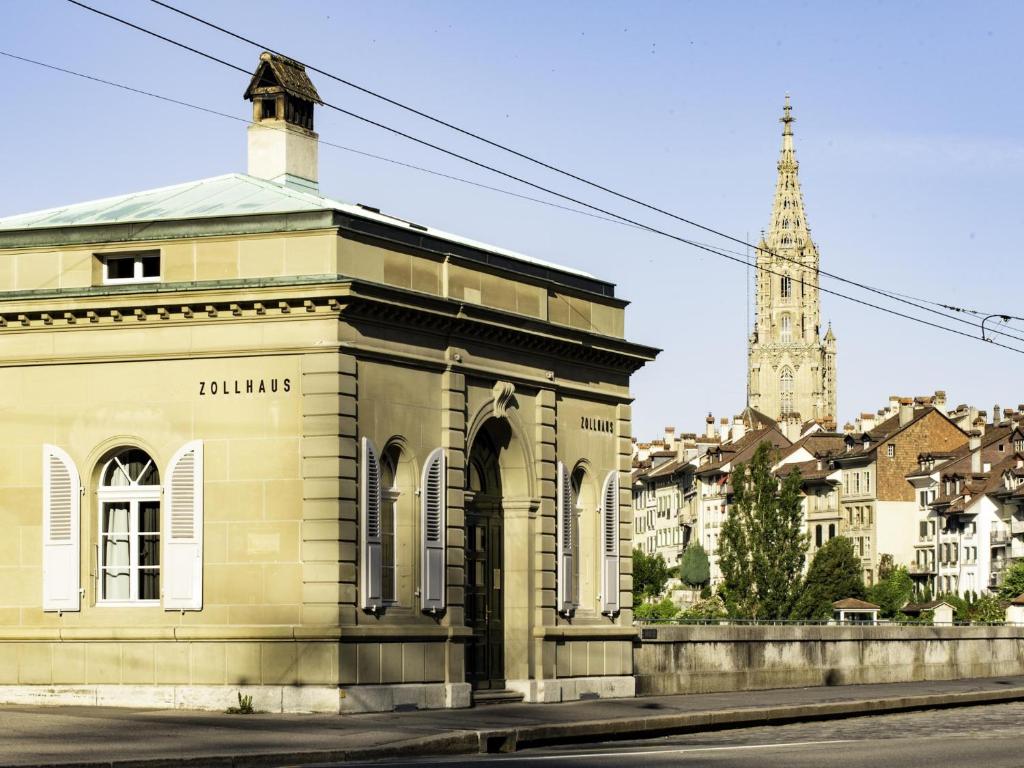 a building on the side of a street with a church at One Suite Hotel - Zollhaus in Bern