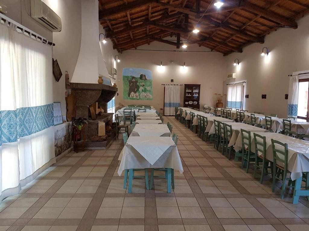 a row of tables in a room with white tables and chairs at Agriturismo Agrifoglio in San Giovanni Suergiu