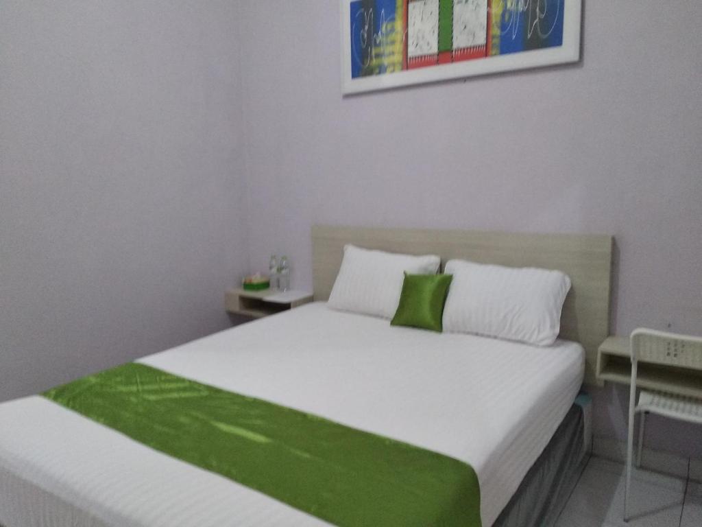 de' GREEN Cibubur في Cibubur: غرفة نوم بسرير ابيض كبير مع شراشف خضراء