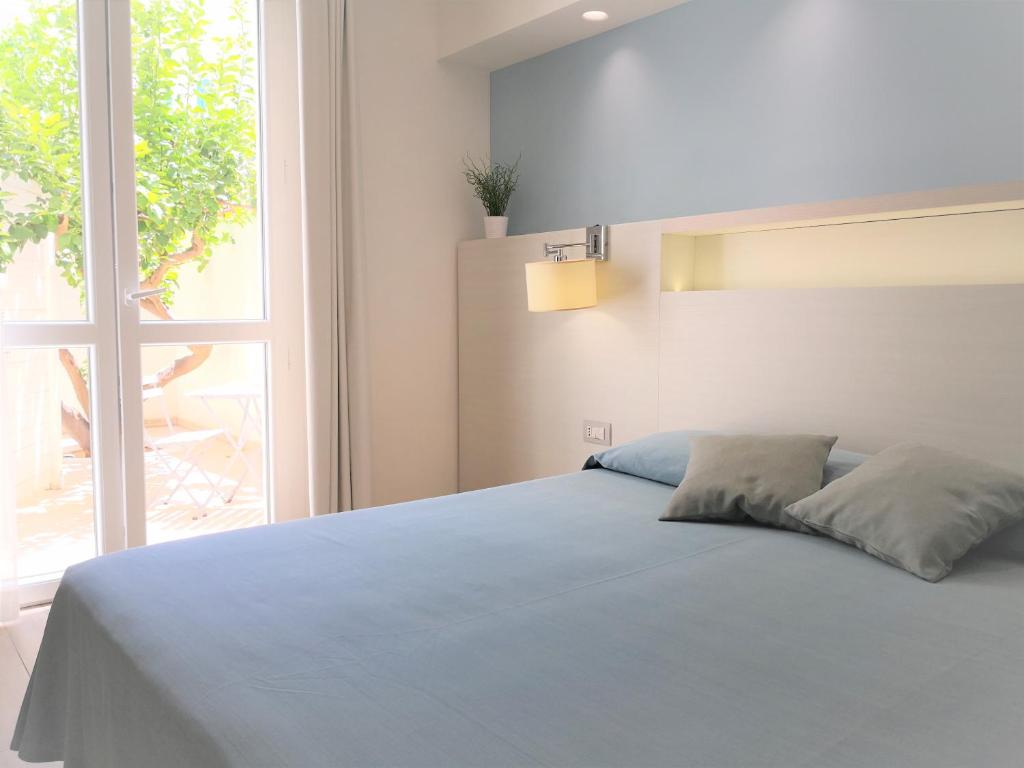 a bedroom with a blue bed with a large window at Hotel Perla Gaia in San Vito lo Capo