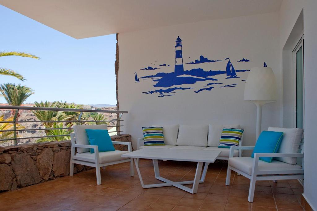 a room with chairs and a table and a lighthouse on the wall at Holiday Club Jardin Amadores in Amadores