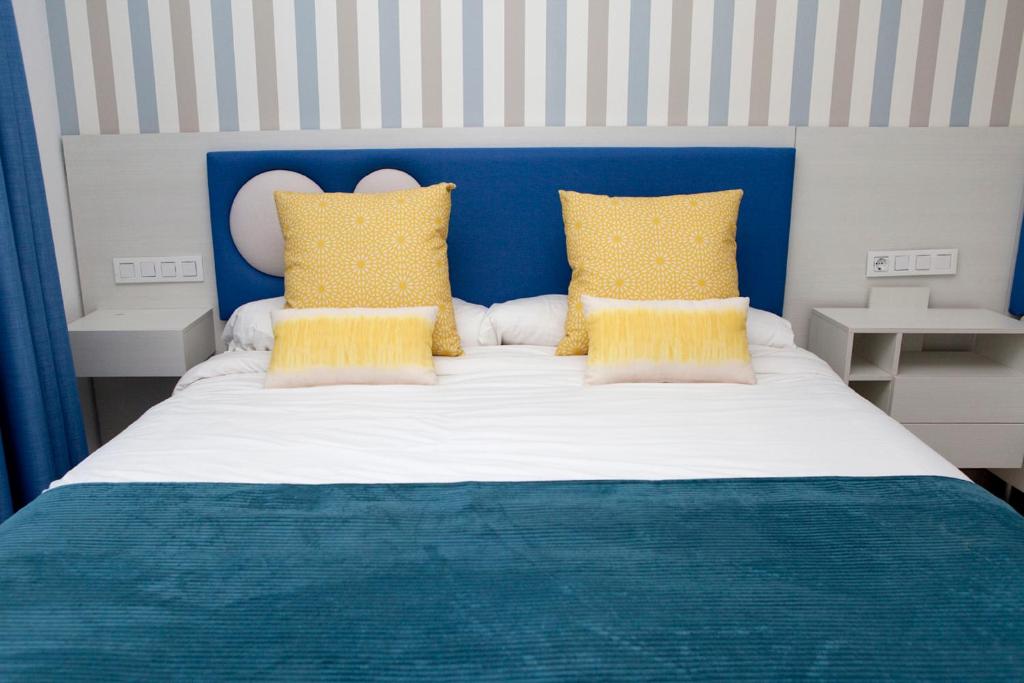 a bed with a blue headboard and yellow pillows at Holiday Club Jardin Amadores in Amadores