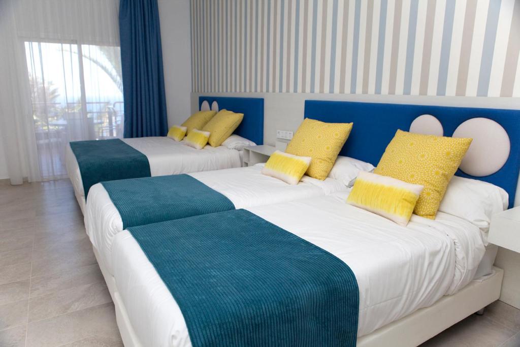 two beds in a room with blue and yellow pillows at Holiday Club Jardin Amadores in Amadores
