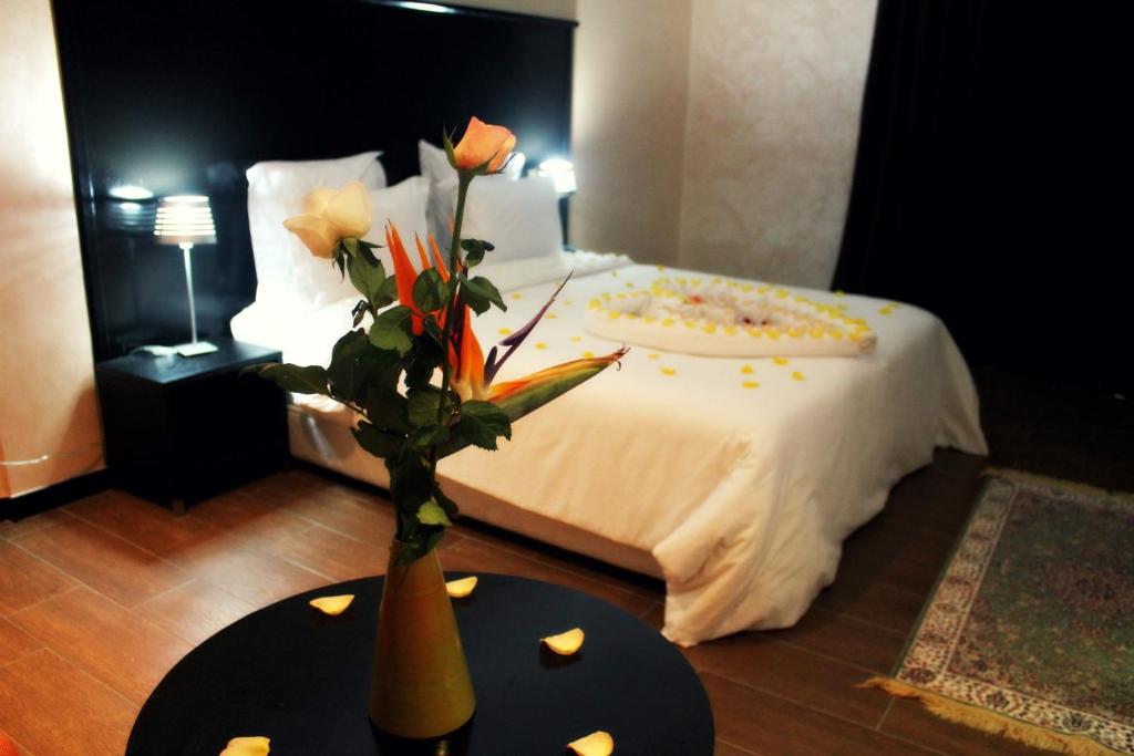 Ubay Hotel في الرباط: غرفة نوم مع سرير مع مزهرية مع الزهور على طاولة