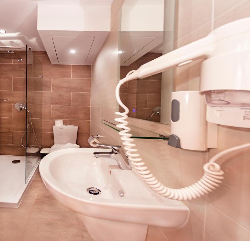 bagno con lavandino bianco e asciugacapelli di Cerviola Hotel a Marsaskala