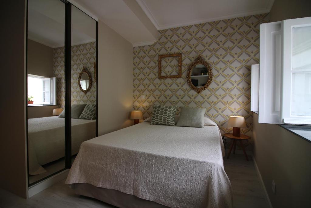 een slaapkamer met een bed en een spiegel bij Nas Três Janelas in Viana do Castelo