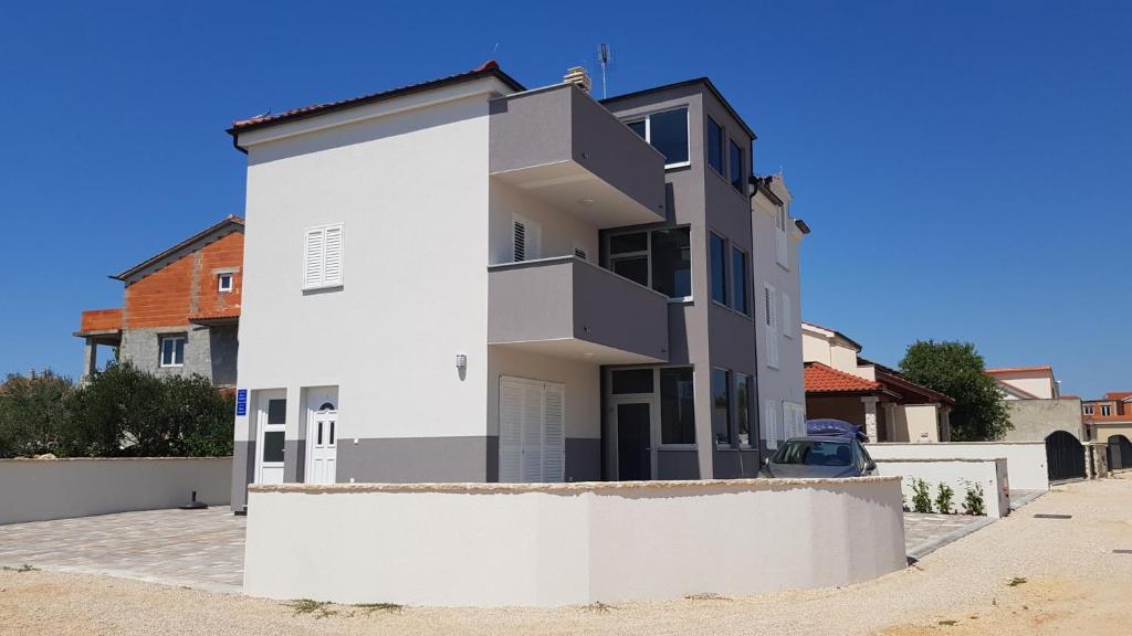 a white house with a white wall at Luminus Apartments in Srima