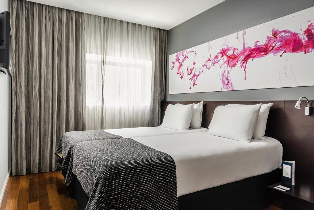 a hotel room with two beds and a painting on the wall at Ikonik Lex in Hospitalet de Llobregat