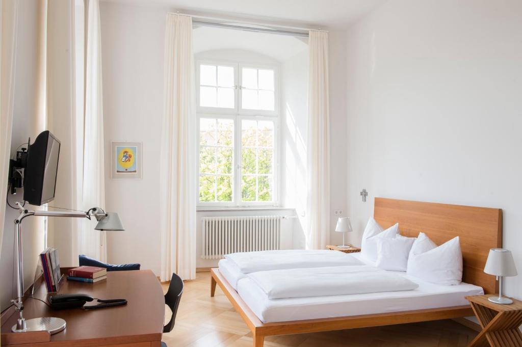 a bedroom with a bed and a desk and a window at Akademie der Dioezese Weingarten in Weingarten