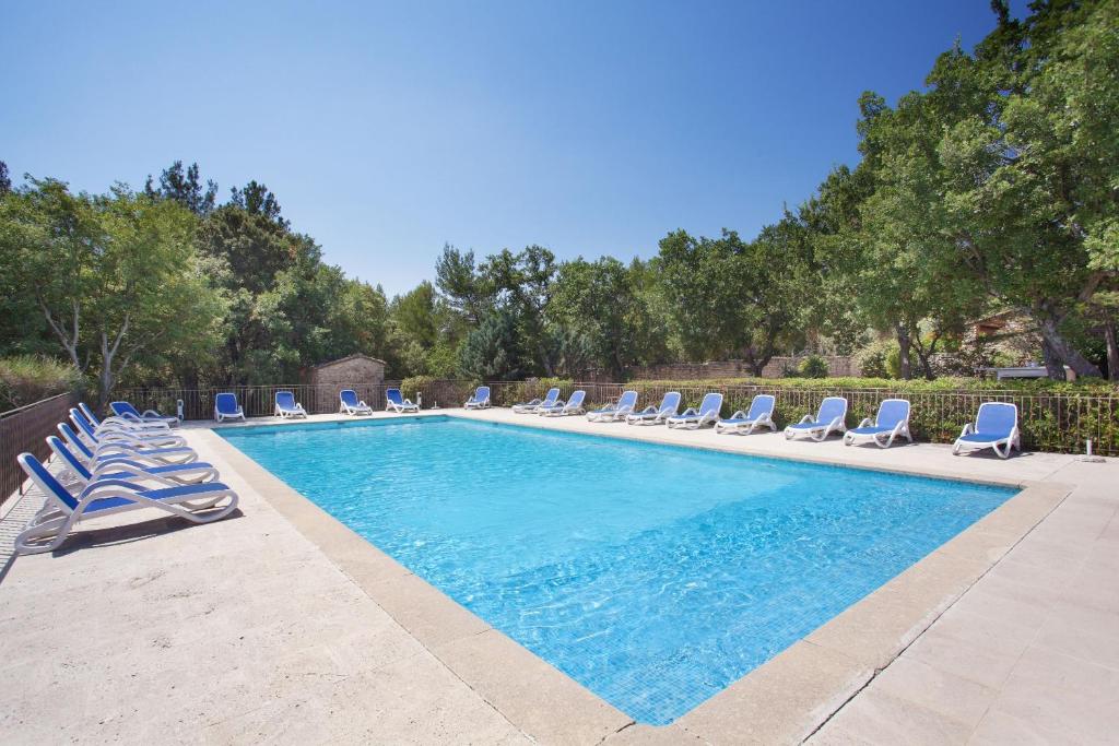 une piscine avec des chaises longues et une piscine dans l'établissement Résidence Prestige Odalys La Bastide des Chênes, à Gordes