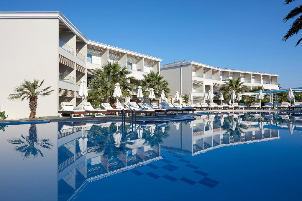 ein Hotel mit einem Pool mit Stühlen und Sonnenschirmen in der Unterkunft Mythos Palace Resort & Spa in Georgioupoli