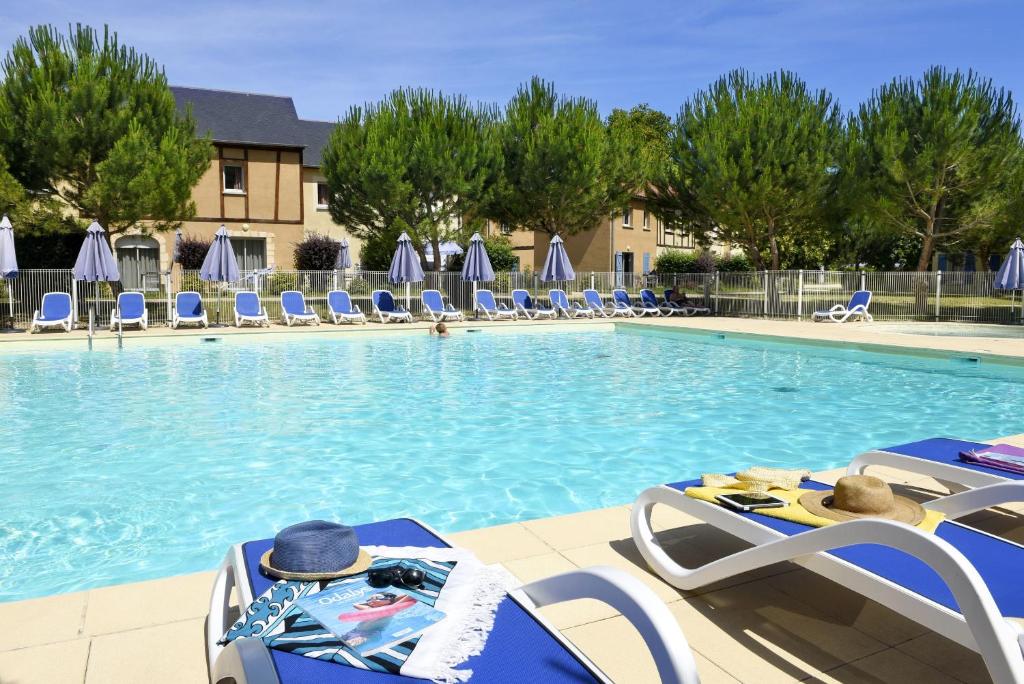 una gran piscina con tumbonas en Résidence Odalys Le Hameau du Moulin, en Montignac