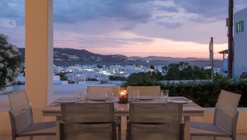 a table with chairs and a candle on a balcony at Traditional Town Home with Amazing View! in Mýkonos City