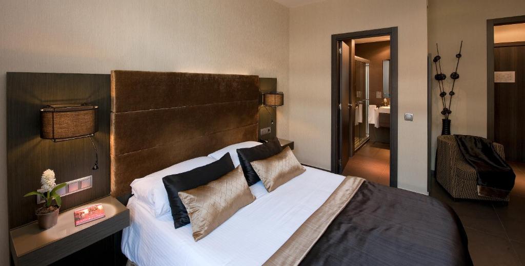 1 dormitorio con 1 cama grande con sábanas y almohadas blancas en Hotel Constanza en Barcelona