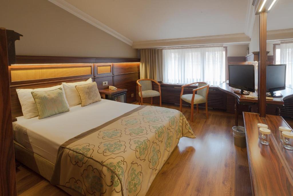 ブルサにあるボユグツェル テルマル ホテルのベッド、デスク、テレビが備わるホテルルームです。