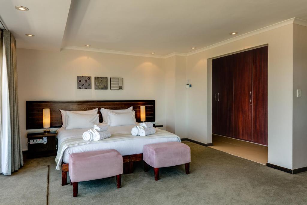 a bedroom with a large white bed with two chairs at 42 On Strathmore in Cape Town