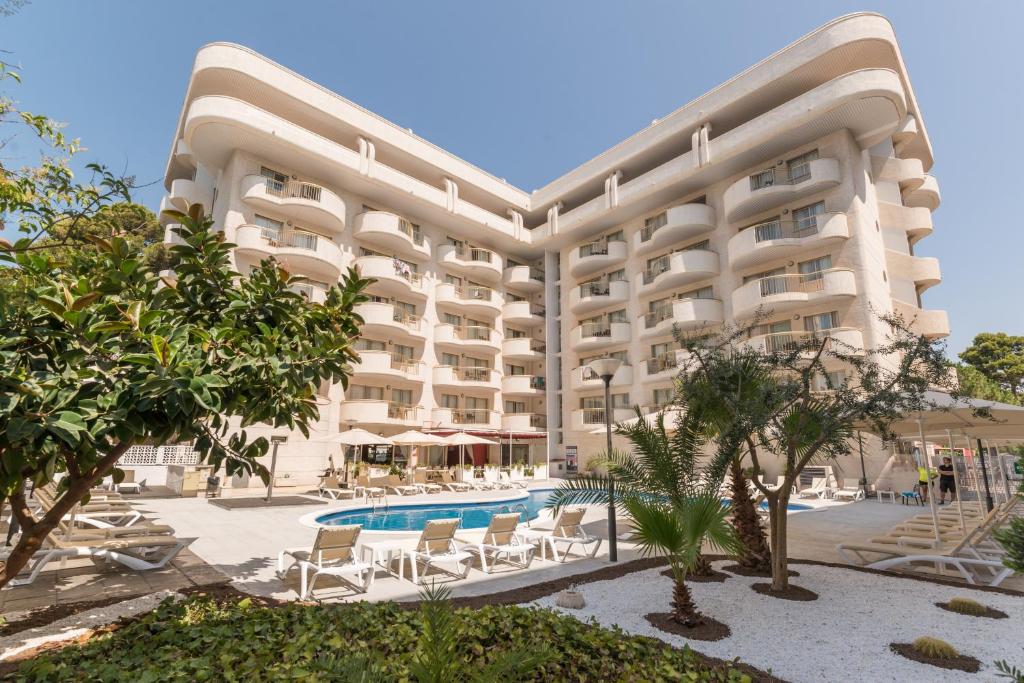un grand hôtel avec une piscine, des chaises et des arbres dans l'établissement Hotel Salou Beach by Pierre & Vacances, à Salou