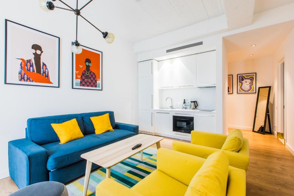 a living room with a blue couch and yellow chairs at HOME/tbilisi in Tbilisi City