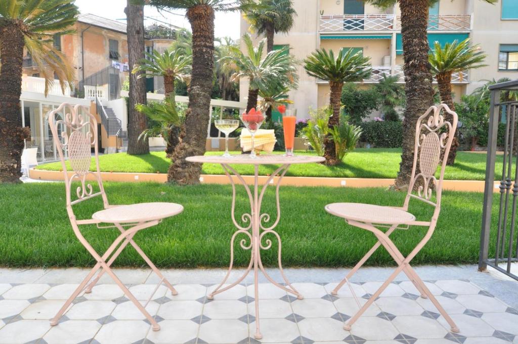 two chairs and a table in a courtyard with palm trees at Mediterraneo Emotional Hotel & Spa in Santa Margherita Ligure