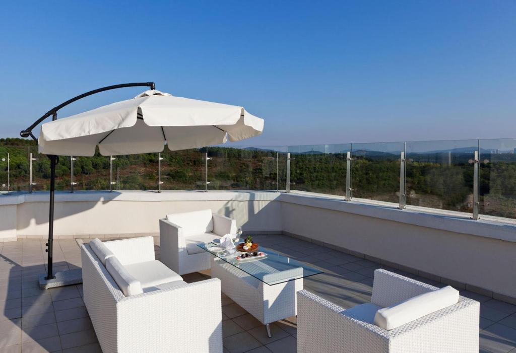 a patio with a table and an umbrella and chairs at Limak Eurasia Luxury Hotel in Istanbul
