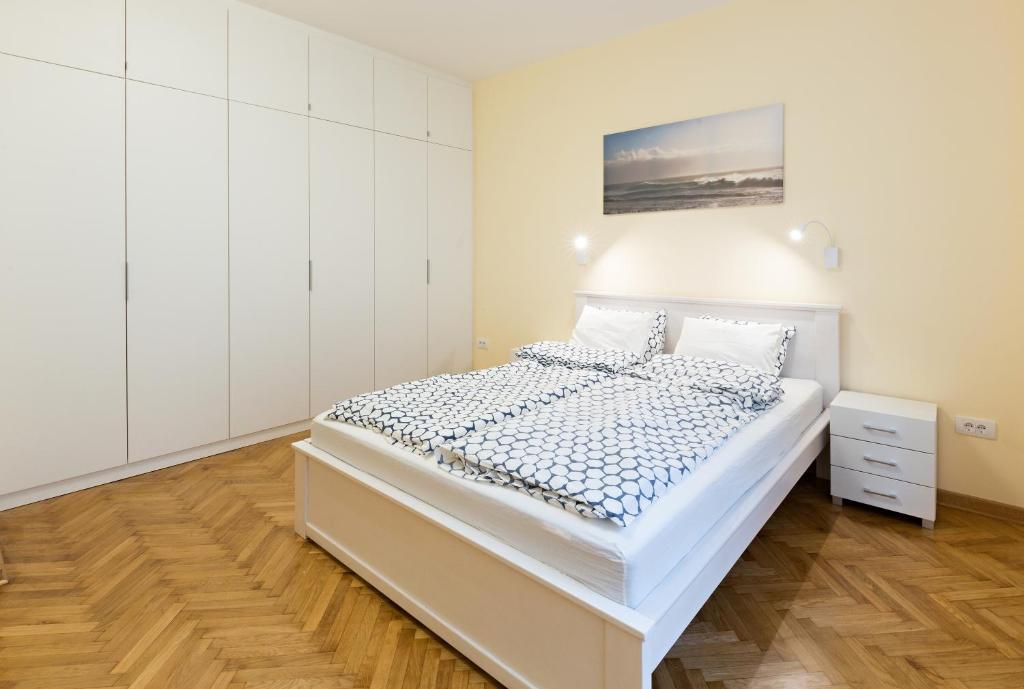 ein weißes Schlafzimmer mit einem Bett und einem Gemälde an der Wand in der Unterkunft Belgrade Center Apartment IV in Belgrad