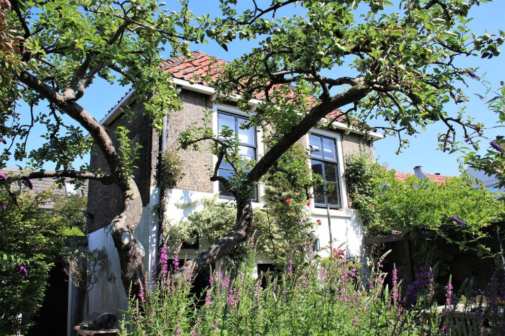 uma casa com flores em frente em Apple Tree Cottage - discover this charming home at beautiful canal in our idyllic garden em Gouda