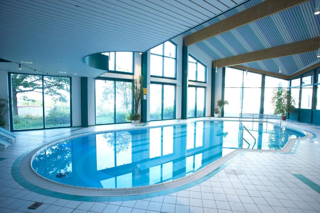 a large swimming pool in a building with windows at Werrapark Familienresort Hotel Heubacher Höhe in Masserberg