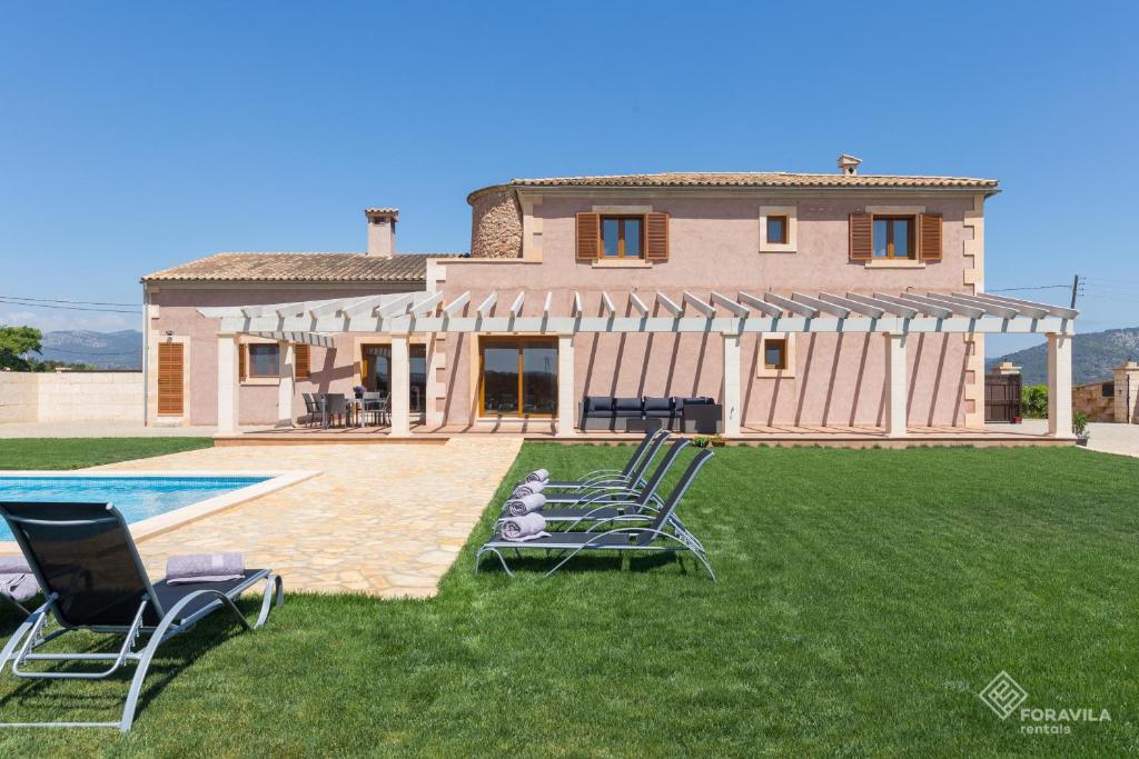 a house with a yard with chairs and a pool at Moli den Sion in Sa Pobla