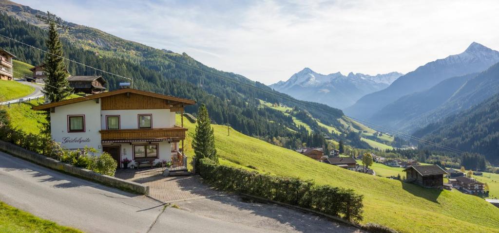 a small house on a hill with mountains in the background at Grübelspitz in Tux