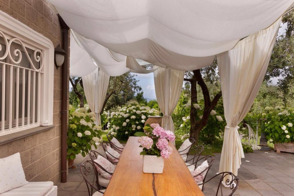 una mesa con un jarrón de flores en un patio en Villa Annabelle, en SantʼAgata sui Due Golfi