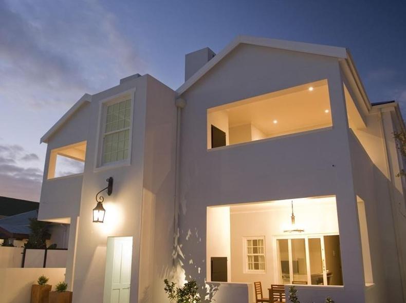 Una gran casa blanca con una fachada iluminada en Kenjockity Self Catering Apartments, en Hermanus