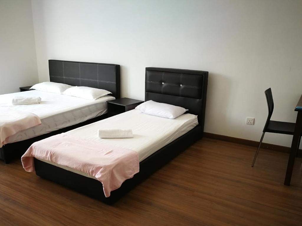 2 camas en una habitación con mesa y silla en Happy Holiday home, en Balik Pulau