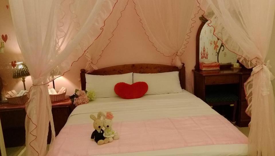 a bed with a heart pillow and two stuffed animals on it at sweet home B&amp;B in Hualien City